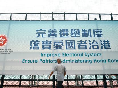 Un hombre pasa este martes ante un cartel en Hong Kong que promueve la reforma del sistema electoral.