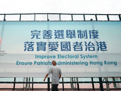 Um homem passa diante de um cartaz que promove a reforma eleitoral, nesta terça-feira, em Hong Kong.