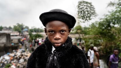 Natan Mahata, 8-year-old school student and sapeur for 3 years, in Kinshasa, 2019.

He wears jacket and hat by Zara, trousers by Place, shirt by Pierre Cardin, suspenders by Boris and shoes by JM Weston.