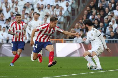 Isco (a la derecha), centrocampista del Real Madrid, presionado por Marcos Llorente, del Atlético de Madrid.