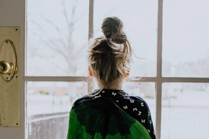 Un niña mira por la ventana durante el confinamiento. 