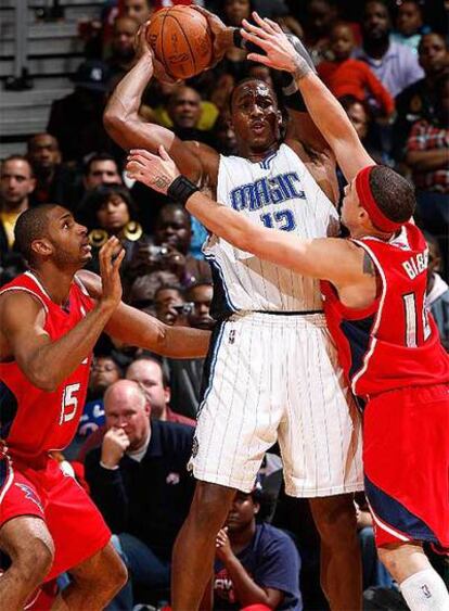 Dwight Howard protege el balón ante dos rivales de Atlanta.