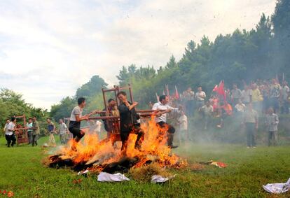 Varios hombres portan una escultura de su dios mientras pasan por una hoguera para celebrar una buena cosecha en el pueblo de Jishui County (China).