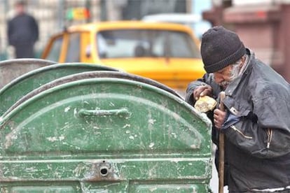 Un hombre recoge pan de un contenedor de basura ayer en Bucarest.