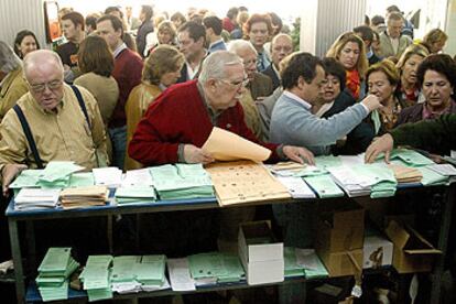 Los electores de un colegio de Sevilla buscan sus papeletas para ejercer su voto.