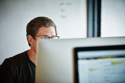 A man works at a computer screeen with graduated spectacles.