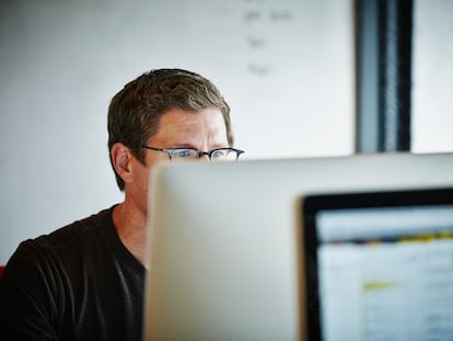 A man works at a computer screeen with graduated spectacles.