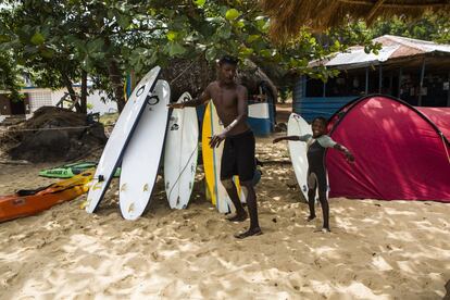 Daniel, uno de los veteranos surfistas, enseña al benjamín del grupo algunos trucos antes de que este entre en el mar.