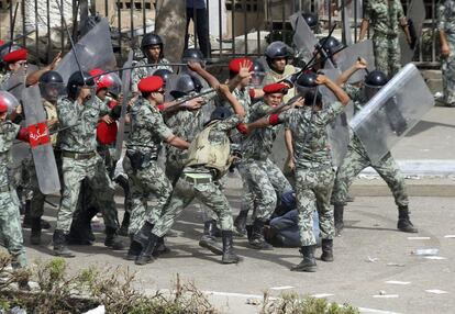 Un militar intenta evitar que sus compañeros sigan pegando con sus porras a un manifestante cerca del Ministerio de Defensa, en El Cairo.