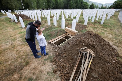 Aljo Mujcic, bosnio, muestra a sus hijos un lugar excavado en el Centro Memorial de Srebrenica-Potocari en Bosnia y Herzegovina, este jueves.
