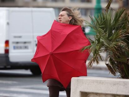 Una mujer se protege del viento en San Sebasti&aacute;n.