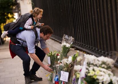 Un padre con su hija deja un ramo de flores en el consulado de Francia, en Madrid. 