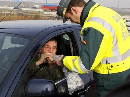 Un conductor realiza una prueba de alcoholemia en un control a instancias de un guardia civil de tráfico.