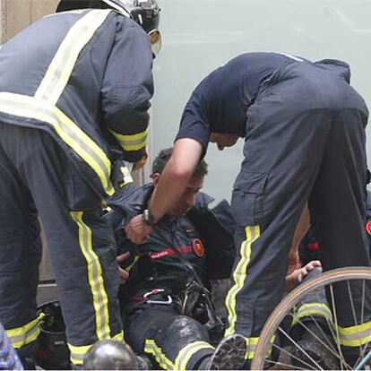Dos bomberos atienden a un compañero afectado por el humo.