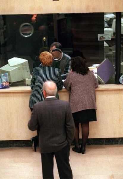 Un grupo de clientes hace cola ante la ventanilla de un banco.