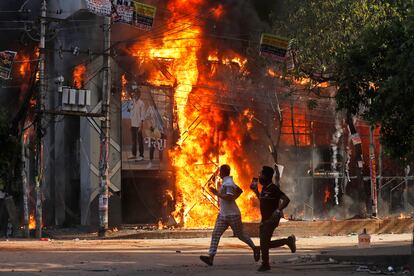 Two men run past a burning shopping mall during protests against Prime Minister Sheikh Hasima on Sunday.