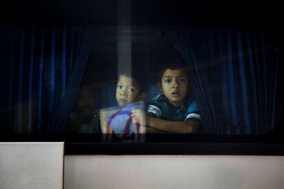 Tres niños miran por la ventana desde un autobús en San Pedro Sula (Honduras) con dirección a México. Las caravanas de centroamericanos, inspiradas por las movilizaciones del año pasado y organizadas por redes sociales, han enfurecido a Trump, quien anunció que desplegará miles de soldados para reforzar la seguridad en su frontera con México.