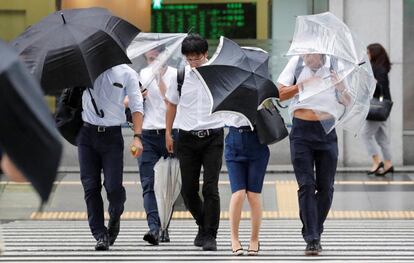 Los transeúntes luchan contra el fuerte viento y la lluvia causados ​​por el tifón Jebi, en Tokio (Japón).