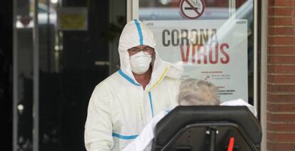 Un sanitario traslada a un paciente enfrente de un centro sanitario. 