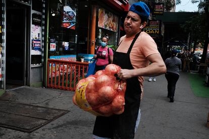 Un trabajador de origen latino carga un costal de cebollas en Manhattan (Nueva York), en junio de 2021.