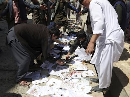 Afganesos recullen documents i fotos de les persones mortes i ferides en l'atemptat d'avui a Kabul.