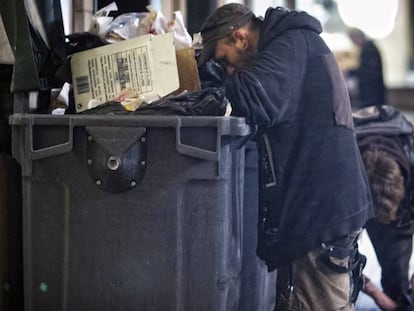 Dos personas buscan restos en un cubo de basura