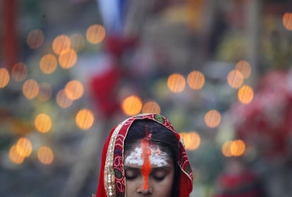 Una mujer nepalí reza durante las ofrendas al sol poniente en las orillas del río Bagmati, en Katmandú (Nepal).