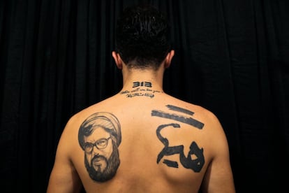 Hamza, 25 años, muestra los tatuajes de su espalda donde se puede ver al líder de Hezbollah, Hassan Nasrallah y eslóganes religiosos musulmanes chiítas que dicen: "La humillación y la derrota está muy lejos de nosotros".