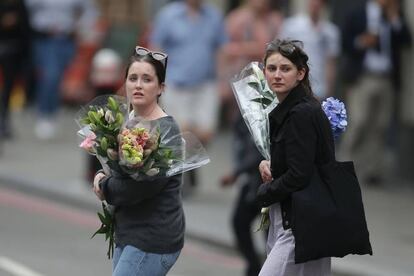Dos jóvenes llevan ramos de flores para depositarlas en una altar improvisado cerca del London Bridge, en Londres.