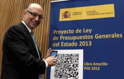 El ministro de Hacienda y Administraciones Públicas, Cristóbal Montoro, posa junto a un cartel con dos códigos QR, que permiten descargar directamente del portal del Ministerio de Hacienda el contenido íntegro de los presupuestos con cualquier teléfono de última generación.