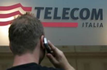 un usuario habla por el m&oacute;vil frente a un cartel de Telecom Italia