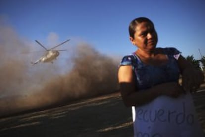 Una mujer con un cartel que apoya a El Americano se retira del sitio donde despega el helicóptero militar que transporta al expolicía rural detenido.