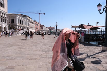 Una turista se refugia del calor bajo un mantón, en Venecia, Italia.