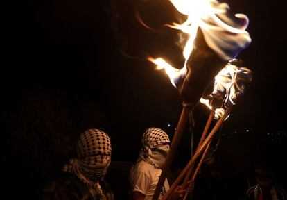 Un grupo de manifestantes palestinos porta antorchas durante una protesta contra los colonos israelíes de Eviatar, cerca de Nablus, Palestina.