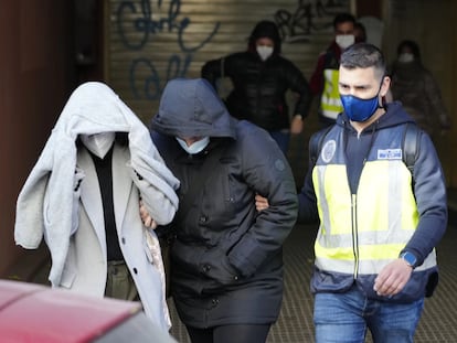 Un agente de la Policía Nacional acompaña a dos de los detenidos en la operación de este lunes en el Ayuntamiento de Cornellà.