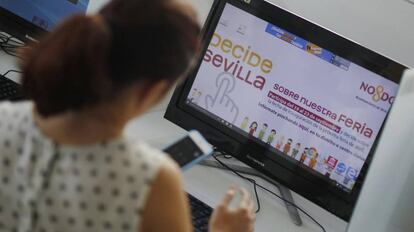 Una sevillana consulta las bases para votar en el referéndum sobre la feria.