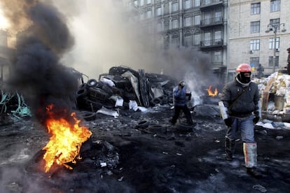  Manifestantes caminan junto a una barricada mientras respetan una tregua con la policía en Kiev (Ucrania), 24 de enero de2014.