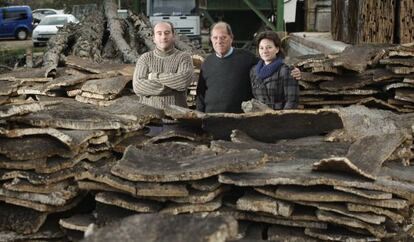 León Miravet, entre sus hijos Adolfo y Herminia, junto a las pilas de planchas de corcho, en su fábrica Espadán Corks, de Soneja.