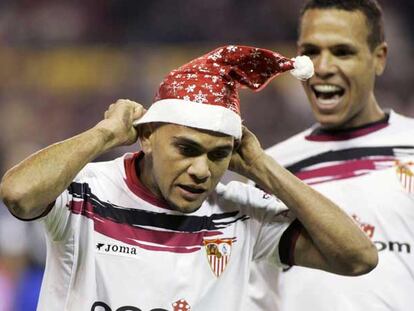 Alves se coloca un gorro de Navidad antes de ser felicitado por Luis Fabiano.