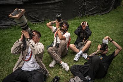 Cuatro personas intentan hacer fotografías del eclipse solar anular, en el planetario de Bogotá, el 14 de octubre.