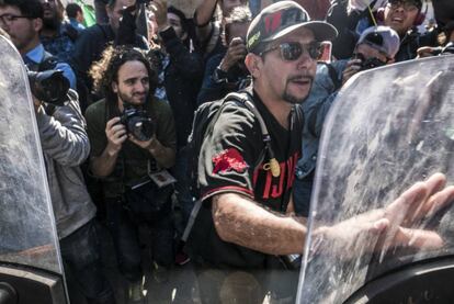 Un manifestante choca con la policía local al intentar ingresar al albergue donde pernocta la caravana de hondureños.