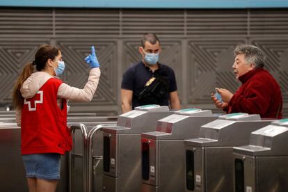 Una voluntaria de la Cruz Roja avisa a una mujer del uso obligatorio de mascarilla en la estación de Atocha de Madrid. La orden que ha entrado en vigor este mismo lunes establece el uso de mascarillas que cubran nariz y boca a todos los usuarios de los servicios de transporte público y colectivo, tanto terrestre, como autobús, taxi, VTC y ferrocarril, como aéreo y marítimo.