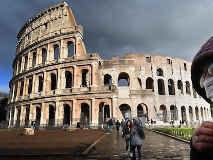 Um homem com máscara diante do Coliseu, em Roma.