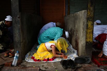 Una niña reza junto a su familia hoy en Nueva Delhi.