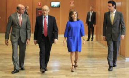 El ministro de Economía y Competitividad, Luis de Guindos (i), el ministro de Hacienda y Administraciones Públicas, Cristóbal Montoro (2i), la vicepresidenta del Gobierno, Soraya Sáez de Santamaría, y el ministro de Industria y Turismo, José Manuel Soria (d), a su llegada hoy para asistir a la toma de posesión del presidente, José María Marín, la vicepresidenta, María Fernández Pérez, y los consejeros de la Comisión Nacional de los Mercados y la Competencia (CNMC), en el Ministerio de Economía y Competitividad.