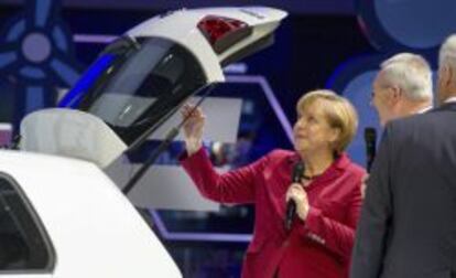 La canciller alemana, Angela Merkel (i), y el presidente de Daimler, Dieter Zetsche, junto a un modelo el&eacute;ctrico de Volkswagen e-Golf, durante la inauguraci&oacute;n del Sal&oacute;n del Autom&oacute;vil de Fr&aacute;ncfort (Alemania).