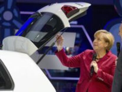 La canciller alemana, Angela Merkel (i), y el presidente de Daimler, Dieter Zetsche, junto a un modelo el&eacute;ctrico de Volkswagen e-Golf, durante la inauguraci&oacute;n del Sal&oacute;n del Autom&oacute;vil de Fr&aacute;ncfort (Alemania).