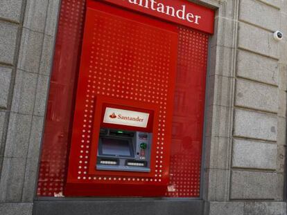 Un hombre cerca de un cajero de Banco Santander y de una oficina de Banco Popular