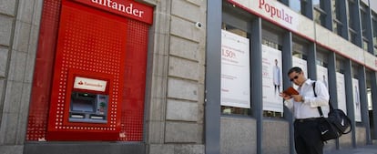 Un hombre cerca de un cajero de Banco Santander y de una oficina de Banco Popular