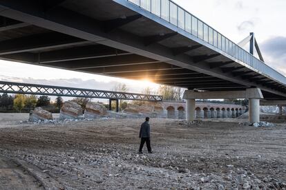 Una persona cruza por el río seco de Aldea del Fresno donde circuló la dana y cuyo puente quedó arrasado.
